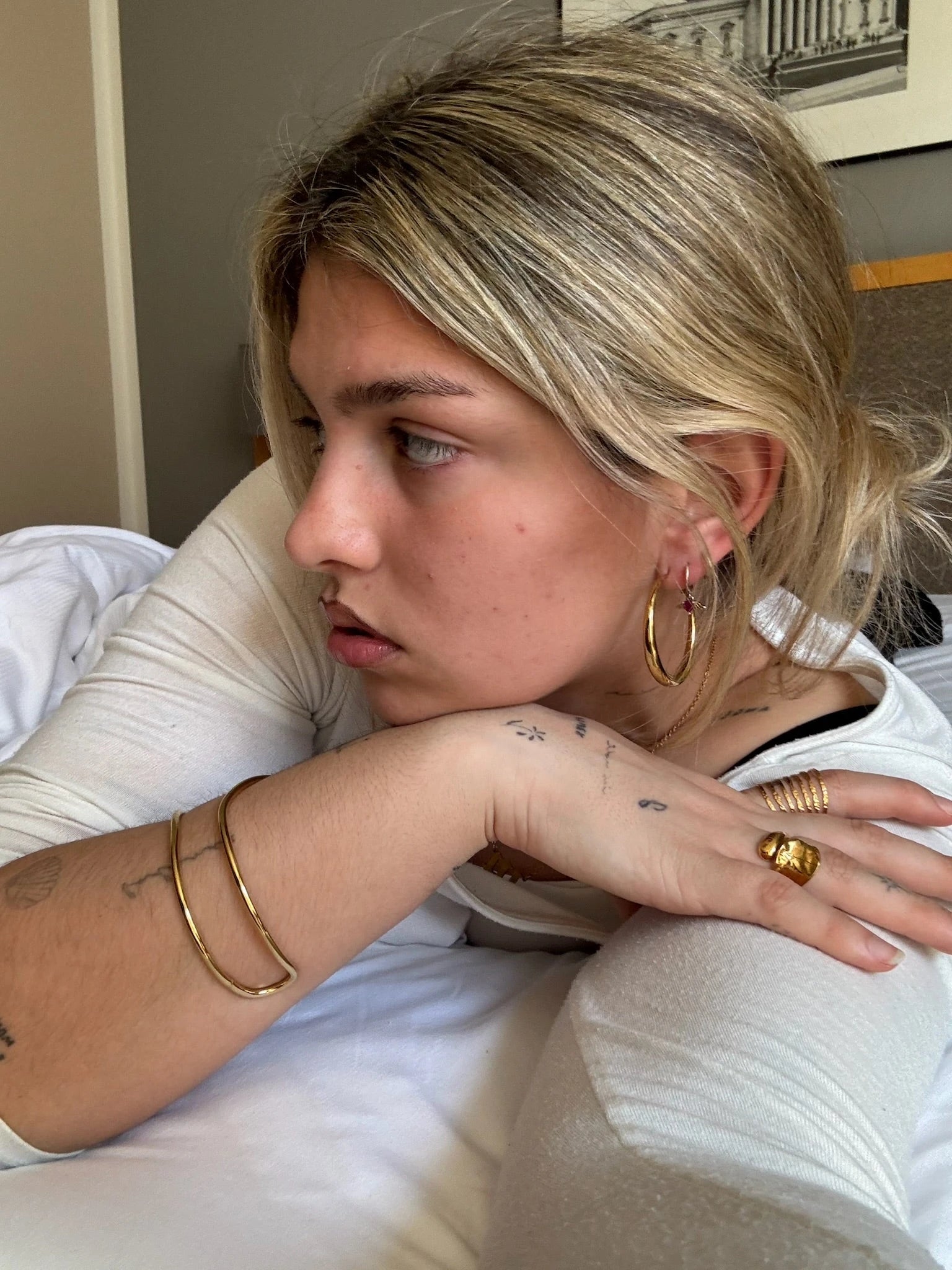 Mujer usando joyas de acero dorado hipoalergénicas y waterproof, aretes, anillos y brazalete.