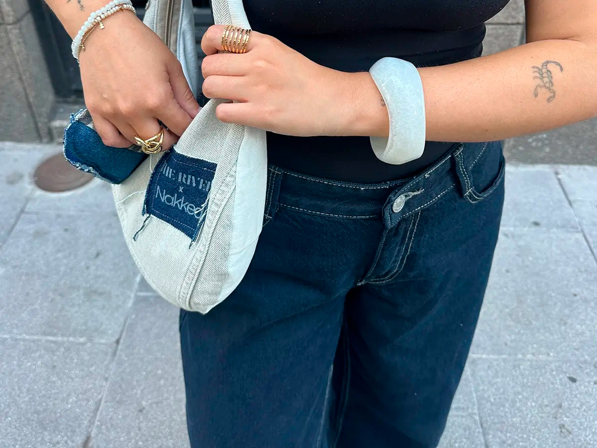 Anillo Paradise acero inoxidable dorado, mujer en la calle con joyas de delacabra, ropa azul, brazalete blanco de delacabra