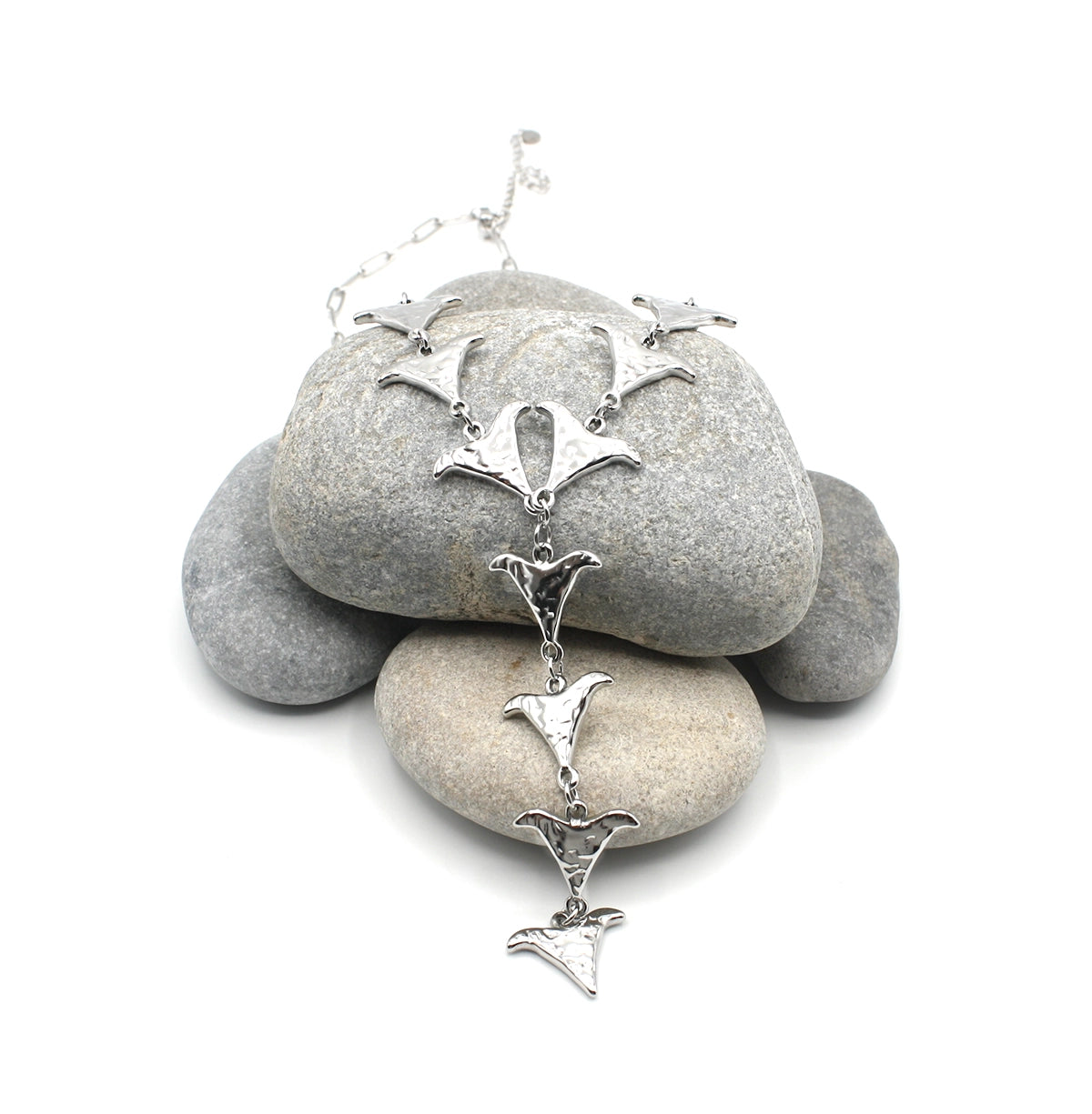 Collar Grace acero inoxidable plateado, luce encima de rocas de río, acabado semirústico brillante, forma geométrica que recuerda una V orgánica. DELACABRA.COM