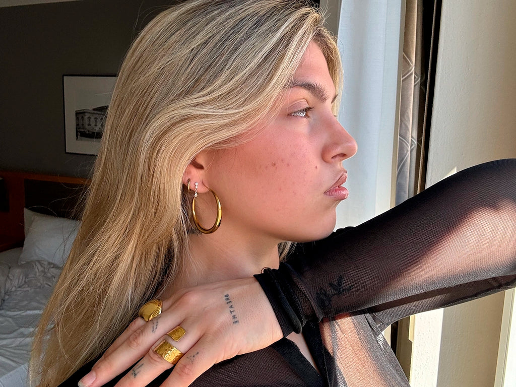 Pendientes Aro Basics acero inoxidable dorado, modelo luciendo conjunto de otros aritos y anillos de delacabra.com, brillo y elegancia sin igual. - DELACABRA