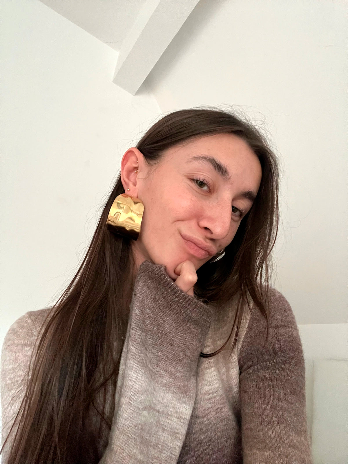 Pendientes Leaf acero inoxidable dorado, mujer luciendo los pendientes con atuendo casual, jersey gris en varios tonos y cabello largo. - DELACABRA