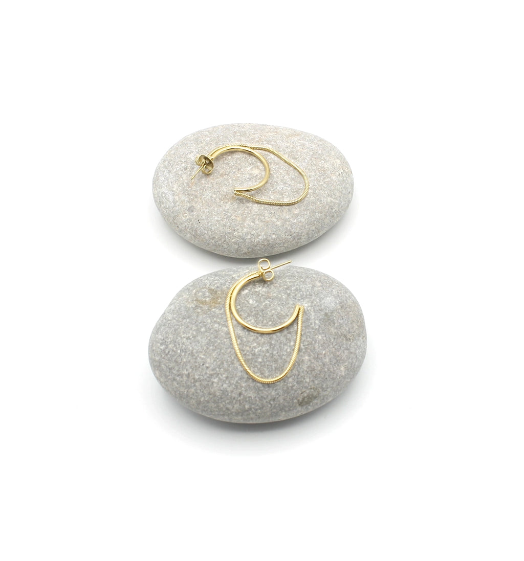 Pendientes Riri acero inoxidable dorado dispuestos en dos rocas, es un aro abierto junto a un lazo dorado que viene unido al aro en cada extremo, un diseño moderno y bellísimo. DELACABRA