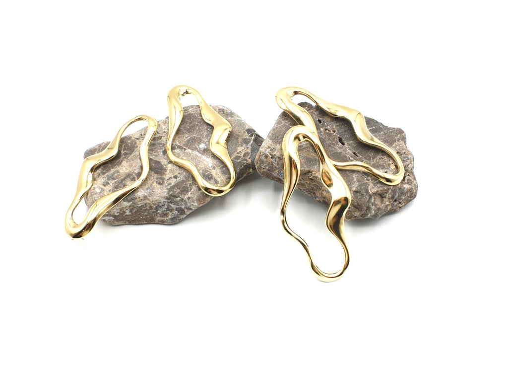 Pendientes Sofía acero inoxidable dorado exhibidos en rocas oscuras, elegantes con dieño moderno y de vanguardía, hipoalergénicos y ligeros. DELACABRA.COM