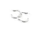 Pareja de aros Caudal plata resaltando su diseño de arco minimalista. Joya de acero amable con la piel DELACABRA.