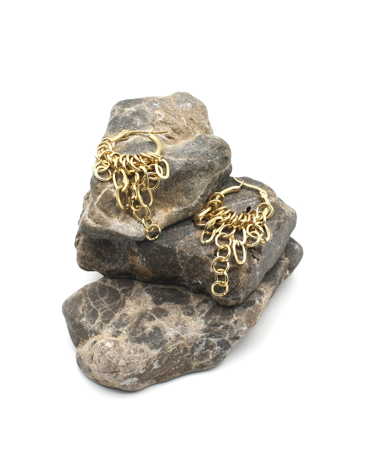 Pendientes de aro Hailey acero inoxidable dorado sobre una cama de rocas de mar oscuras, aro con diseño de cadenas colgantes con efecto dinámico y sofisticado. DELACABRA