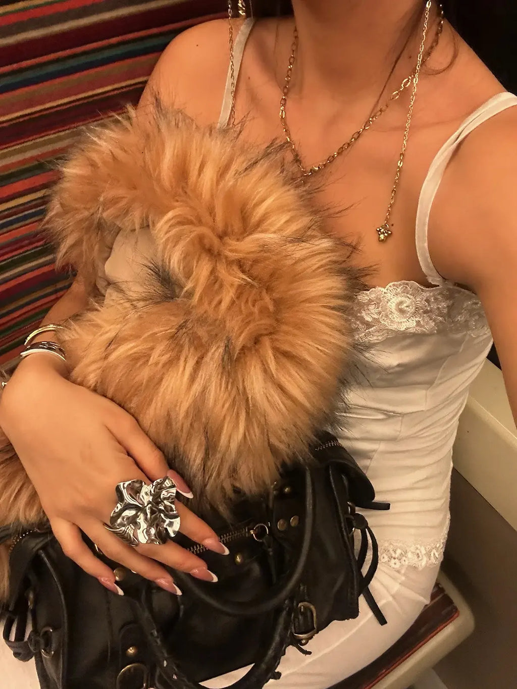 Anillo Lys acero inoxidable plateado ajustable, mujer luciendo el anillo lys de delacabra vestido elegante de escote.bolso de cuero negro y abrigo de piel. Delacabra