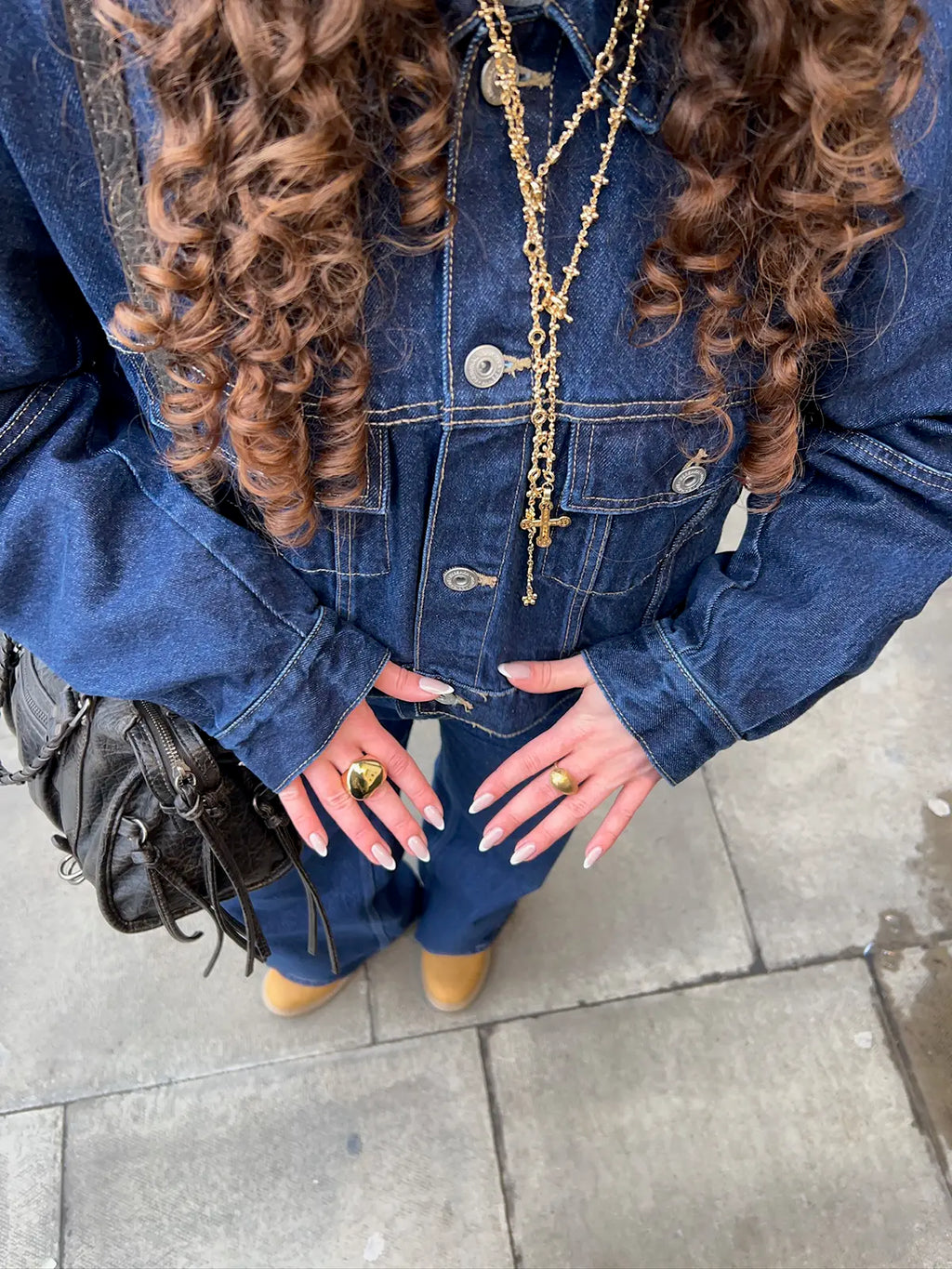 Anillo Angelito acero inoxidable dorado, mujer en la calle visitiendo un cojunto azul con cadena larga y anillo angelito de Delacabra