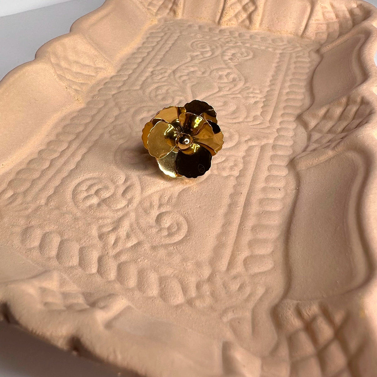 Anillo de flor ajustable en acero inoxidable dorado sobre bandeja decorativa beige