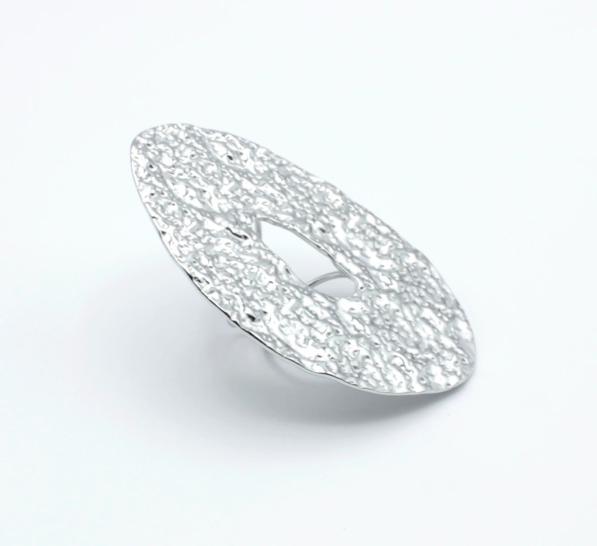 Anillo ajustable GLOOM de DELACABRA en acero inoxidable plateado, con forma ovalada, textura martillada orgánica y abertura central, vista en ángulo