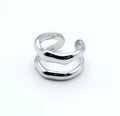 Anillo plateado con dos bandas curvas paralelas, de acero inoxidable brillante, diseño abierto y estructura ajustable.