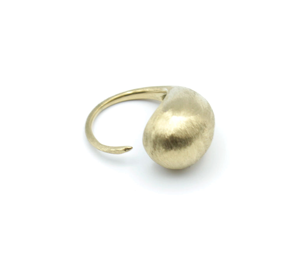 Vista superior del anillo DROP en acero inoxidable dorado, diseño ajustable con forma de gota fluida y acabado mate con textura cepillada