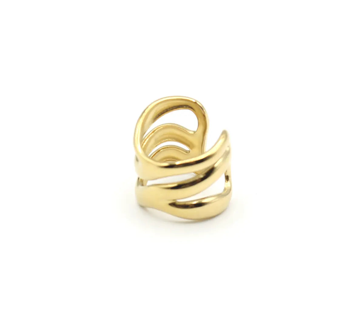 Primer plano del Anillo Nilo de acero dorado en una superficie gris. Se aprecian las tres bandas onduladas y asimétricas, un diseño calado y moderno. Es un anillo abierto y ajustable.