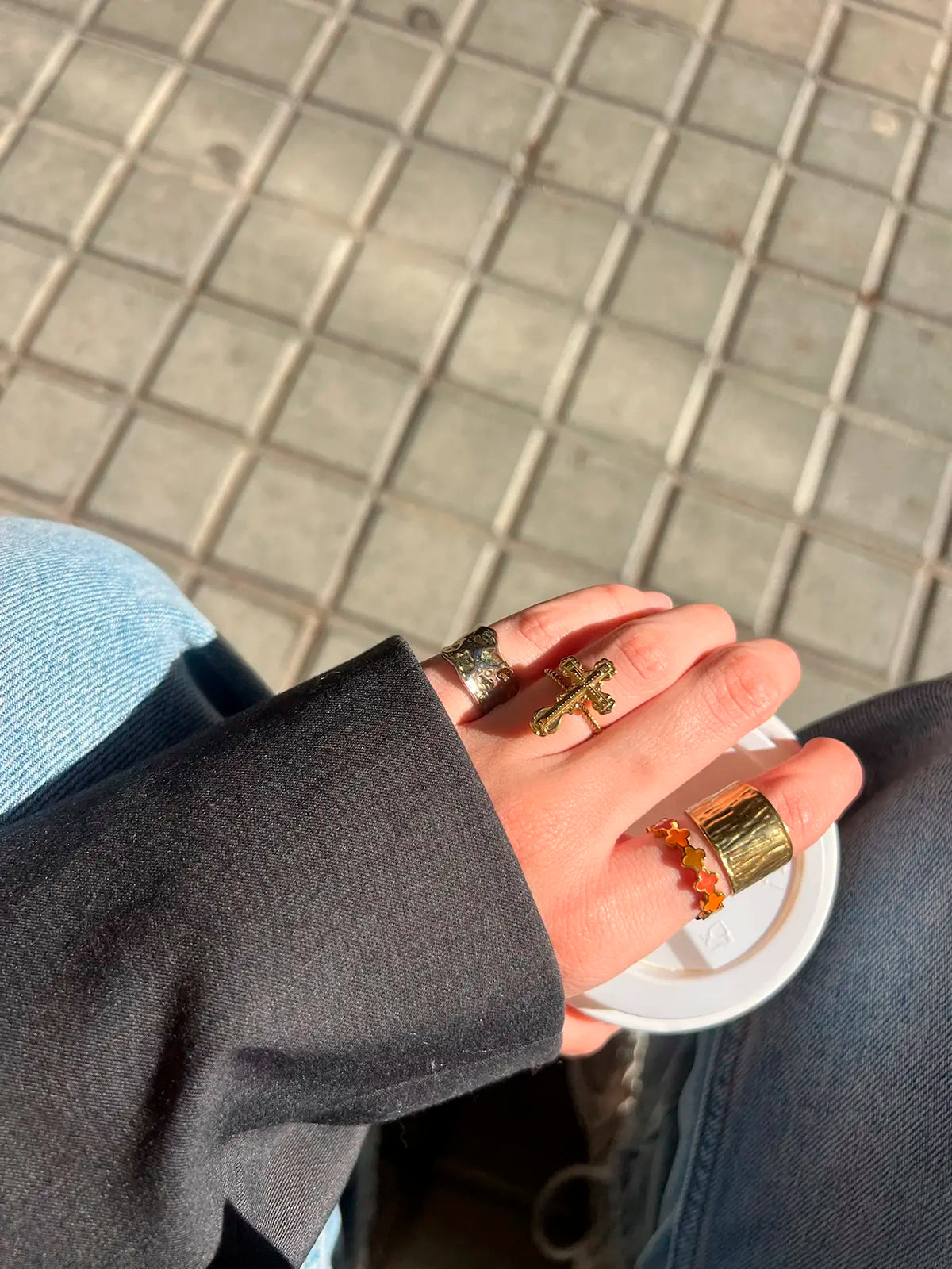 Mujer luciendo el Anillo Paz marca delacabra, acero inoxidable ajustable dorado en conjunto con otros anillos, luz natural. DELACABRA