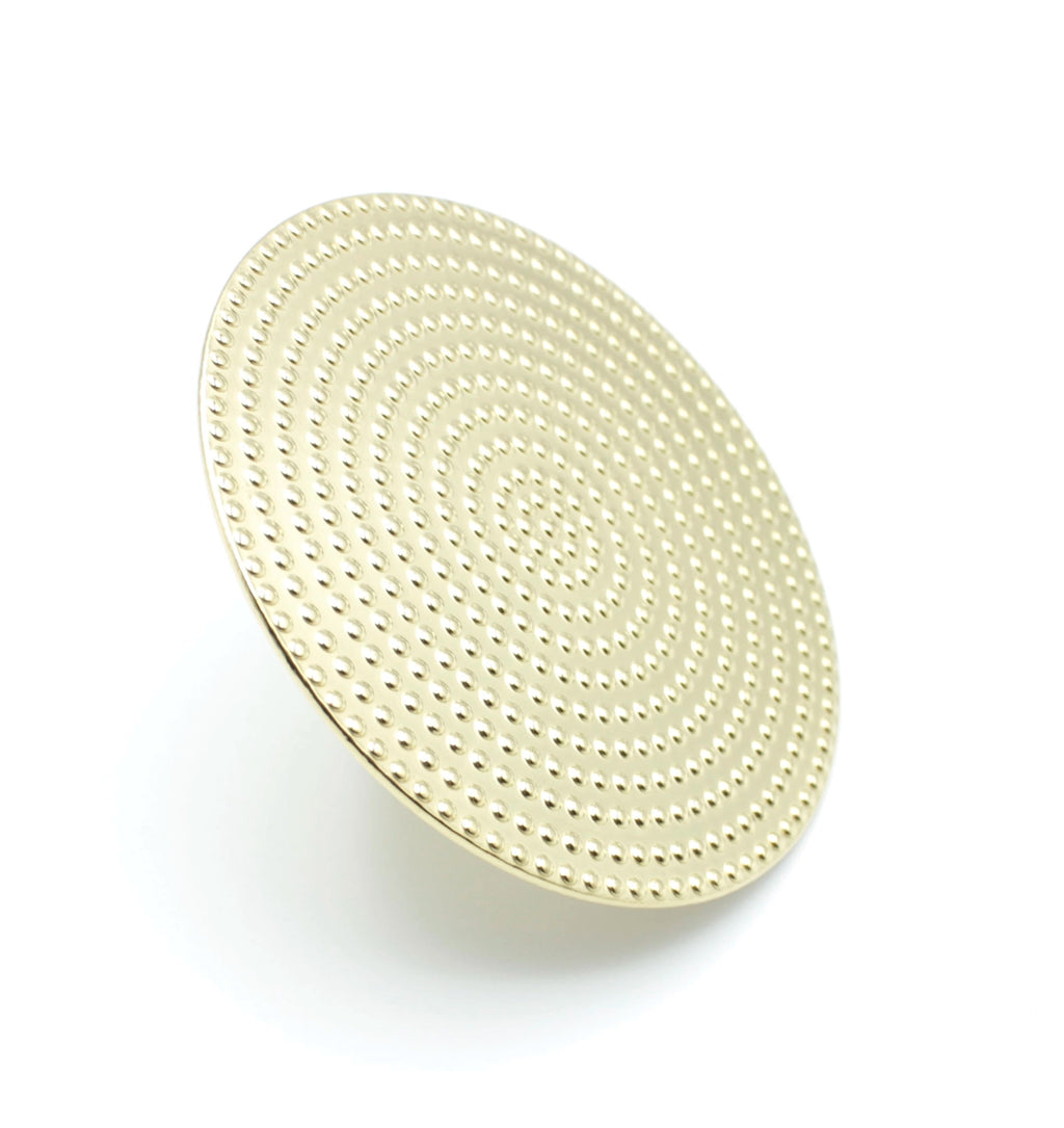 Vista superior del anillo SHIELD de DELACABRA en acabado dorado, diseño circular con textura de puntos en ondas concéntricas, fabricado en acero inoxidable y ajustable