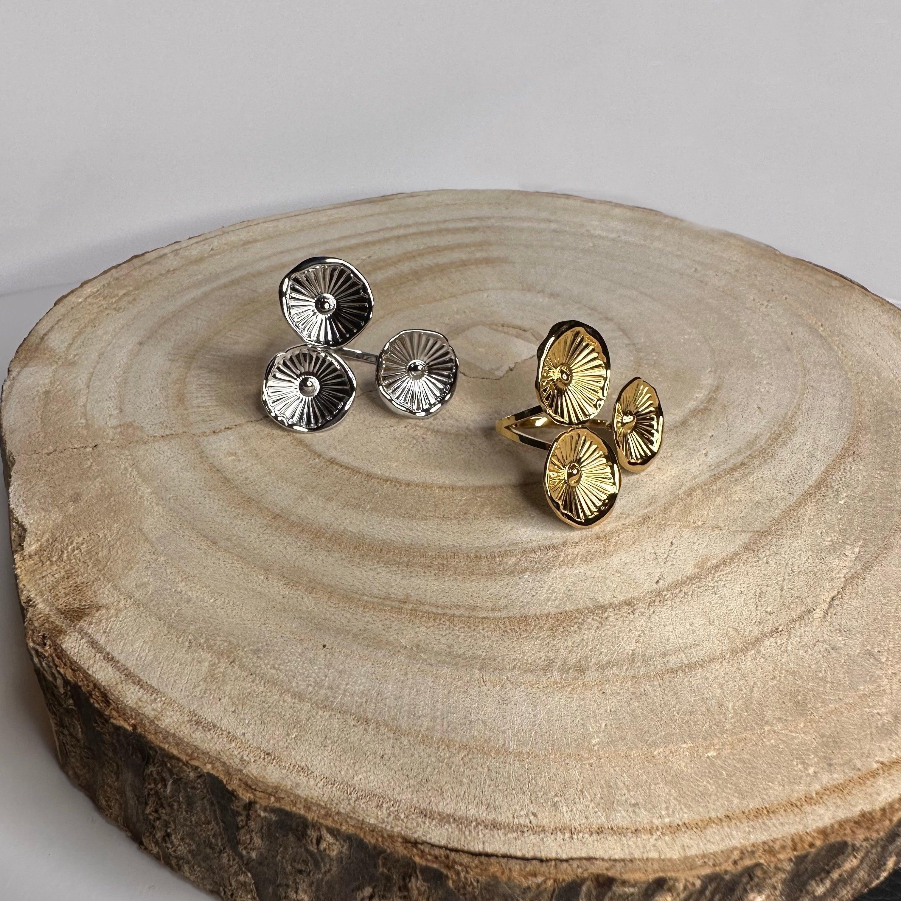 Anillos ajustables de acero inoxidable dorado y plateado con diseño circular sobre madera.