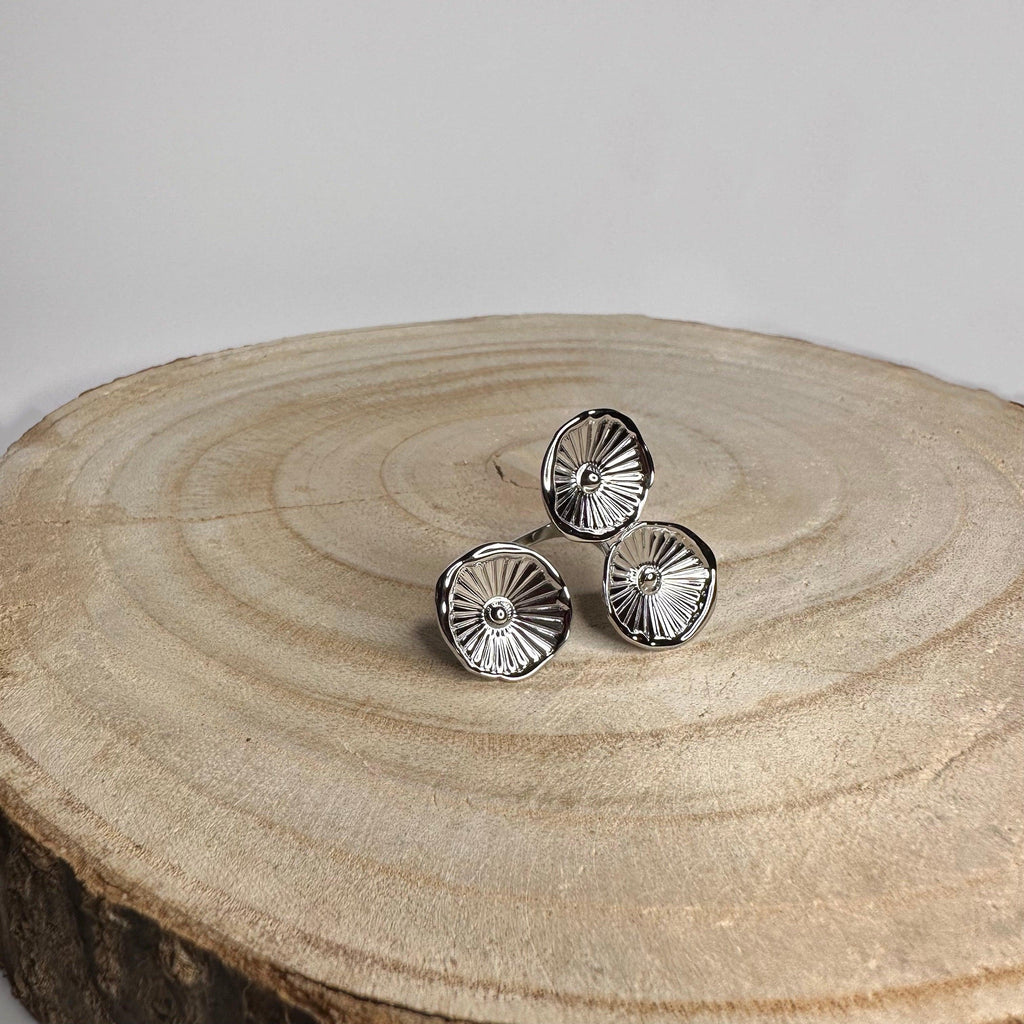 Anillo Triz ajustable en acero inoxidable plateado, con tres flores talladas y acabado brillante. Hipoalergénico y cómodo para uso diario.