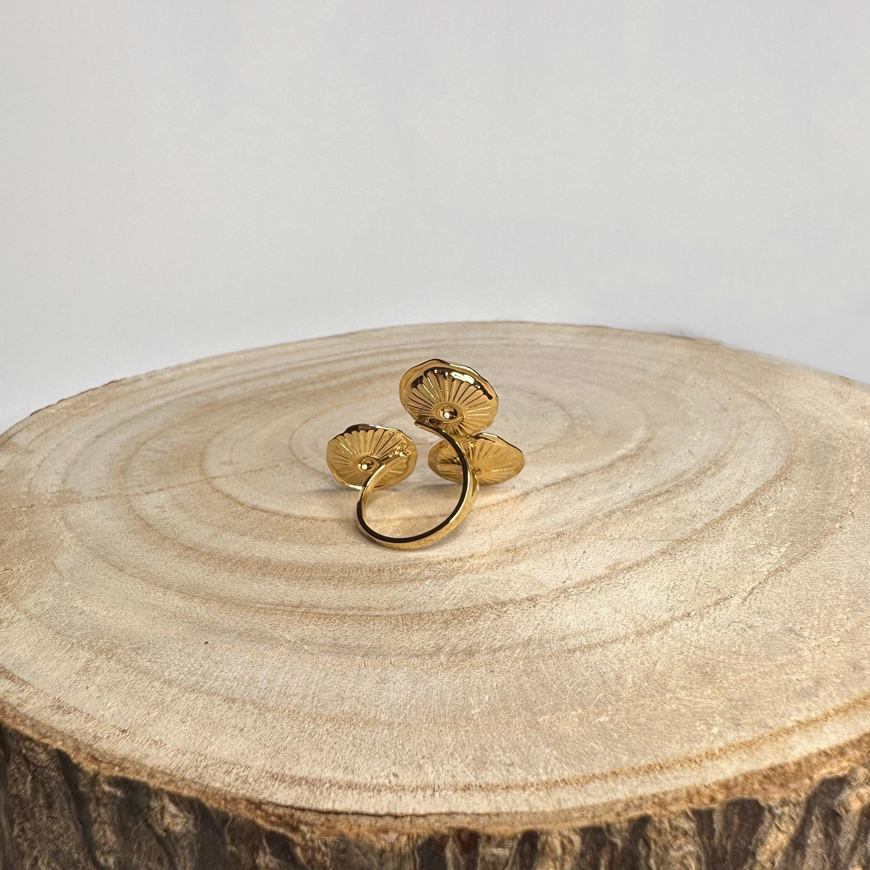 anillo ajustable dorado de acero inoxidable con diseño de flores, vista trasera sobre madera