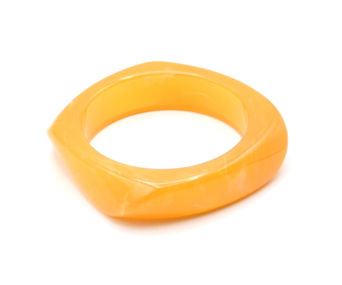 Vista lateral de la pulsera Amber naranja con superficie pulida y bordes redondeados. -DELACABRA