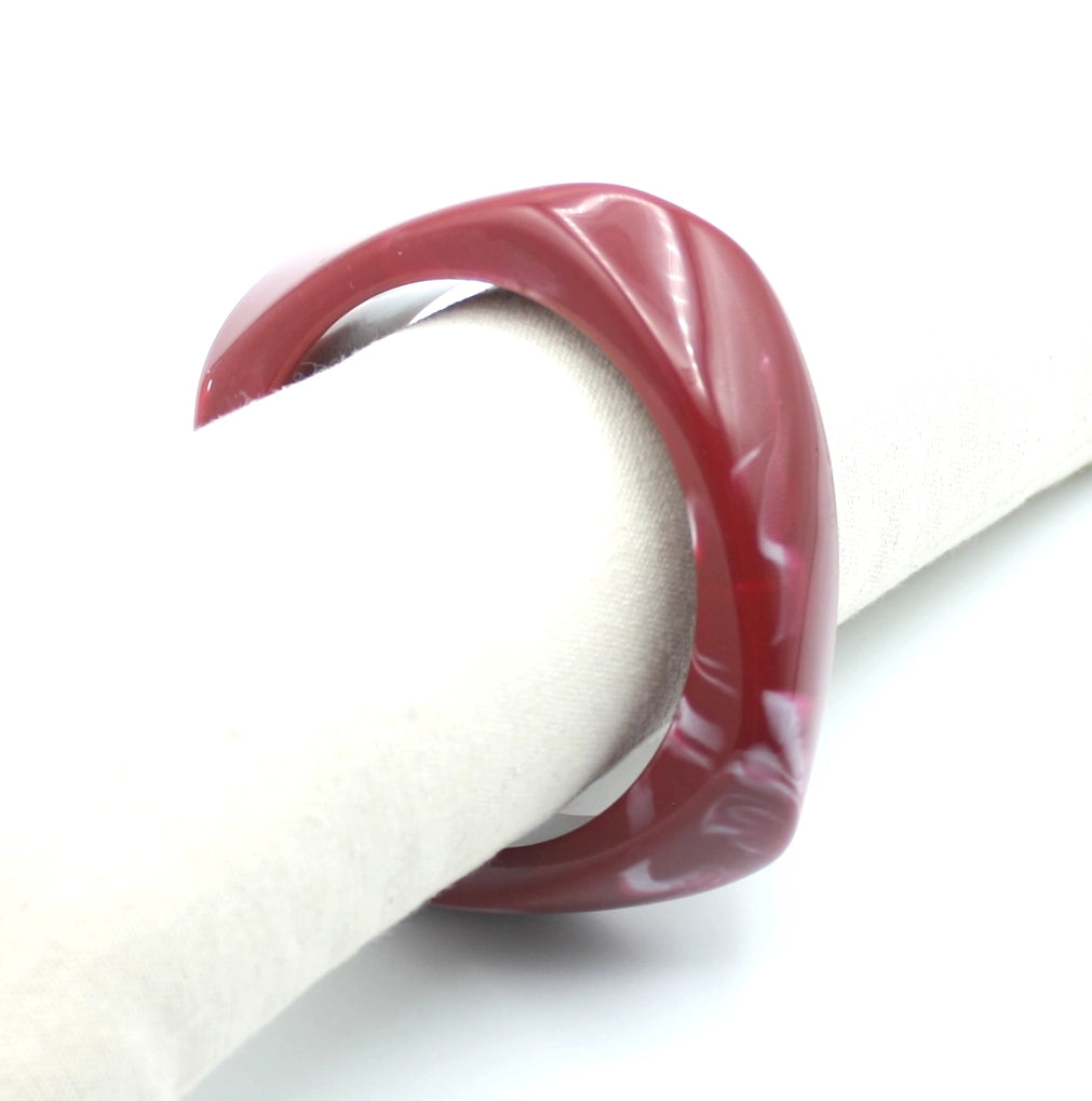 Pulsera Amber de resina roja con efecto nacarado, presentada sobre soporte textil. - DELACABRA