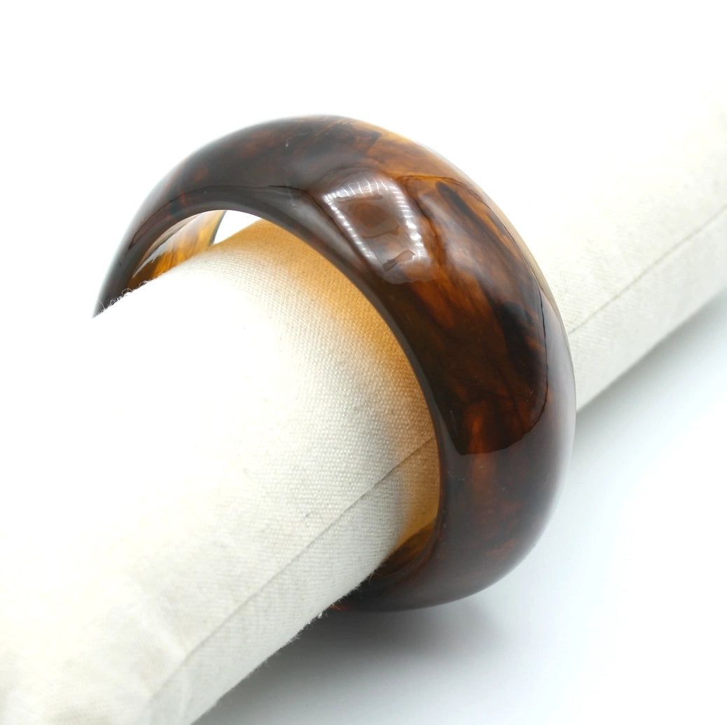 Brazalete Aura en resina marrón con vetas translúcidas y acabado pulido sobre expositor - DELACABRA