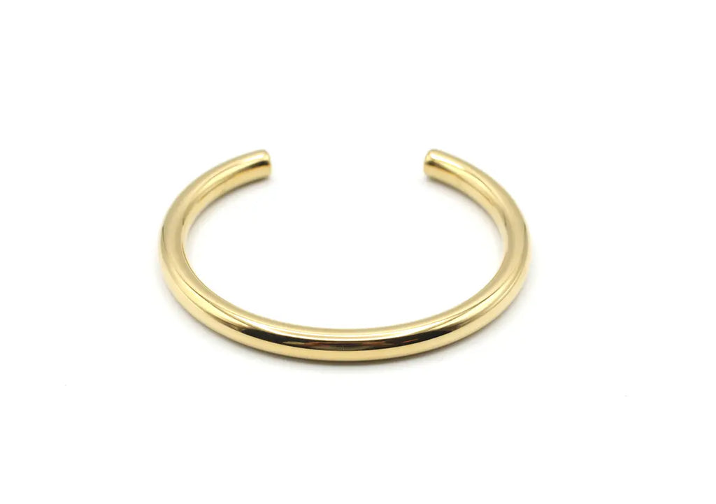 Vista frontal del brazalete Lia dorado de acero con estructura rígida y abierta. Joya amable con la piel DELACABRA.