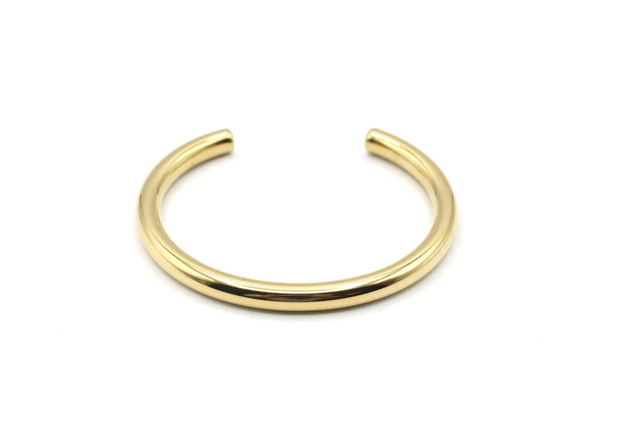 Vista frontal del brazalete Lia dorado de acero con estructura rígida y abierta. Joya amable con la piel DELACABRA.