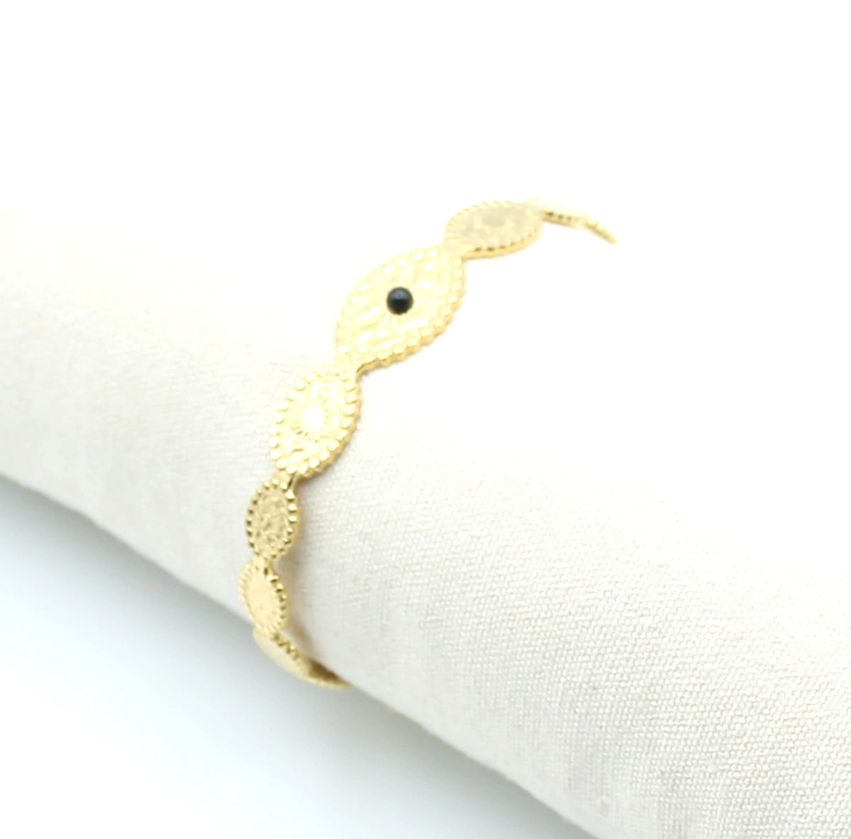 Brazalete Onde de acero inoxidable dorado ajustable, estructura abierta con labrado de soles en un expositor de tela -DELACABRA
