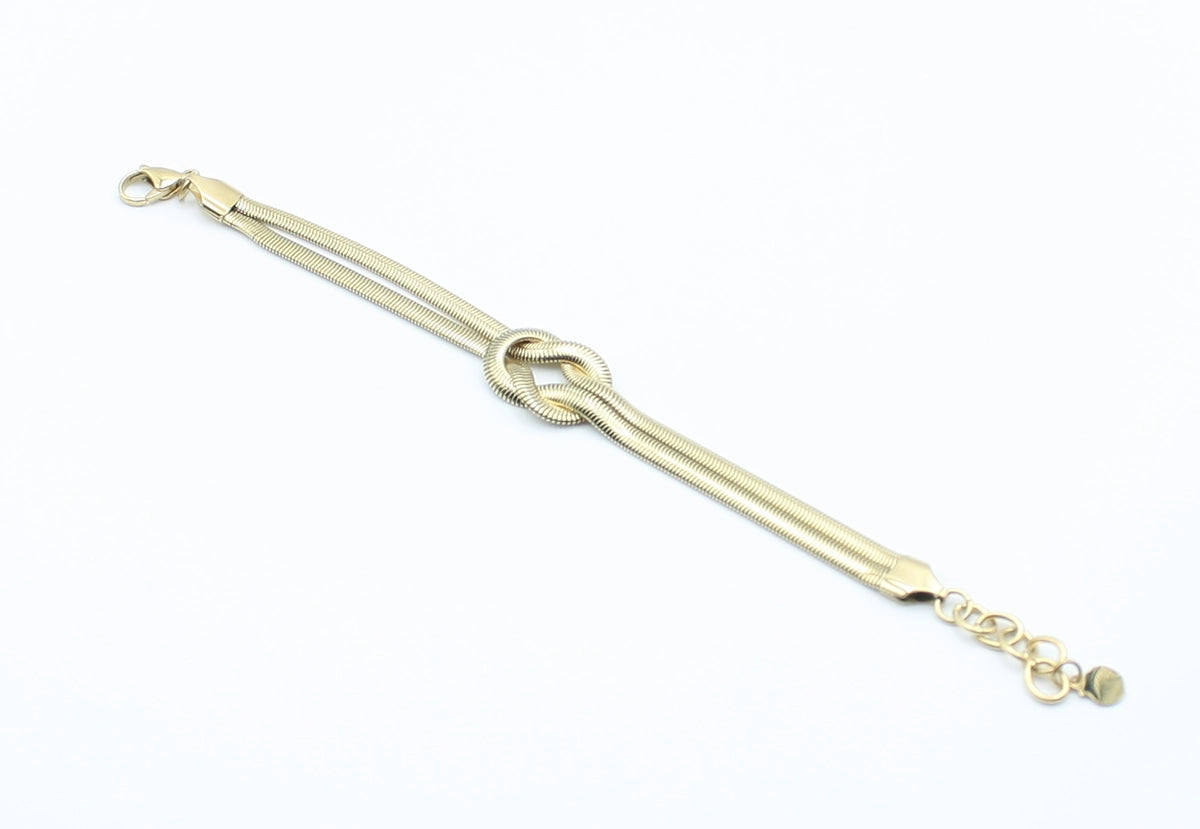 Brazalete Tangled acero inoxidable dorado entrelazado simulando un nudo llano, acabado suave y brillante - DELACABRA
