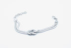 Brazalete Tangled acero inoxidable plateado entrelazado simulando un nudo llano, acabado suave y brillante - DELACABRA