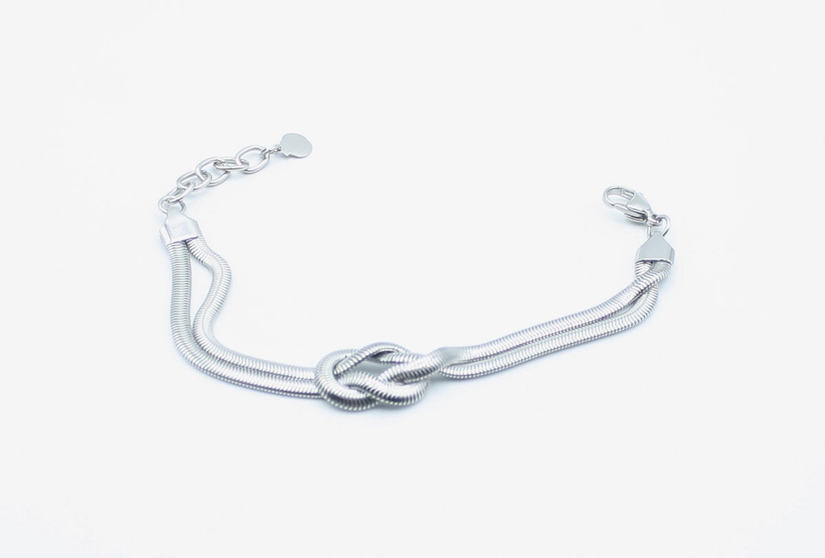 Brazalete Tangled acero inoxidable plateado entrelazado simulando un nudo llano, acabado suave y brillante - DELACABRA