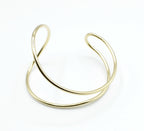 Brazalete Tiana dorado en acero inoxidable, doble aro con curvas enfrentadas estilo abierto, hipoalergénico, resistente al agua, ajustable y duradero -DELACABRA