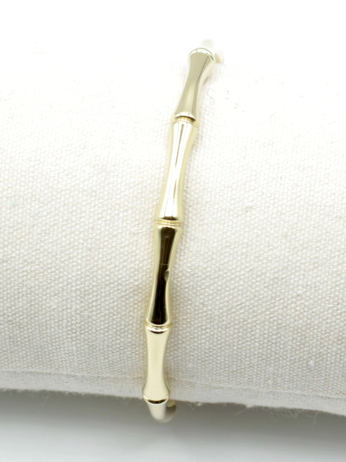 Brazalete dorado con forma de caña de bamboo sobre soporte blanco, acabado pulido, acero inoxidable hipoalergénico, resistente al agua, ajustable y duradero -DELACABRA