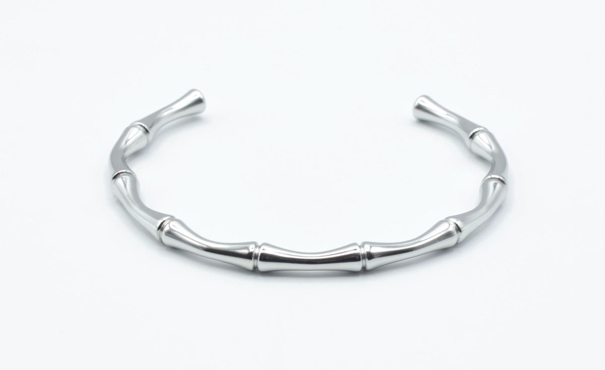 Brazalete estilo bamboo en acero inoxidable plateado visto desde arriba, con forma simétrica y pulido brillante, hipoalergénico, resistente al agua, ajustable y duradero -DELACABRA