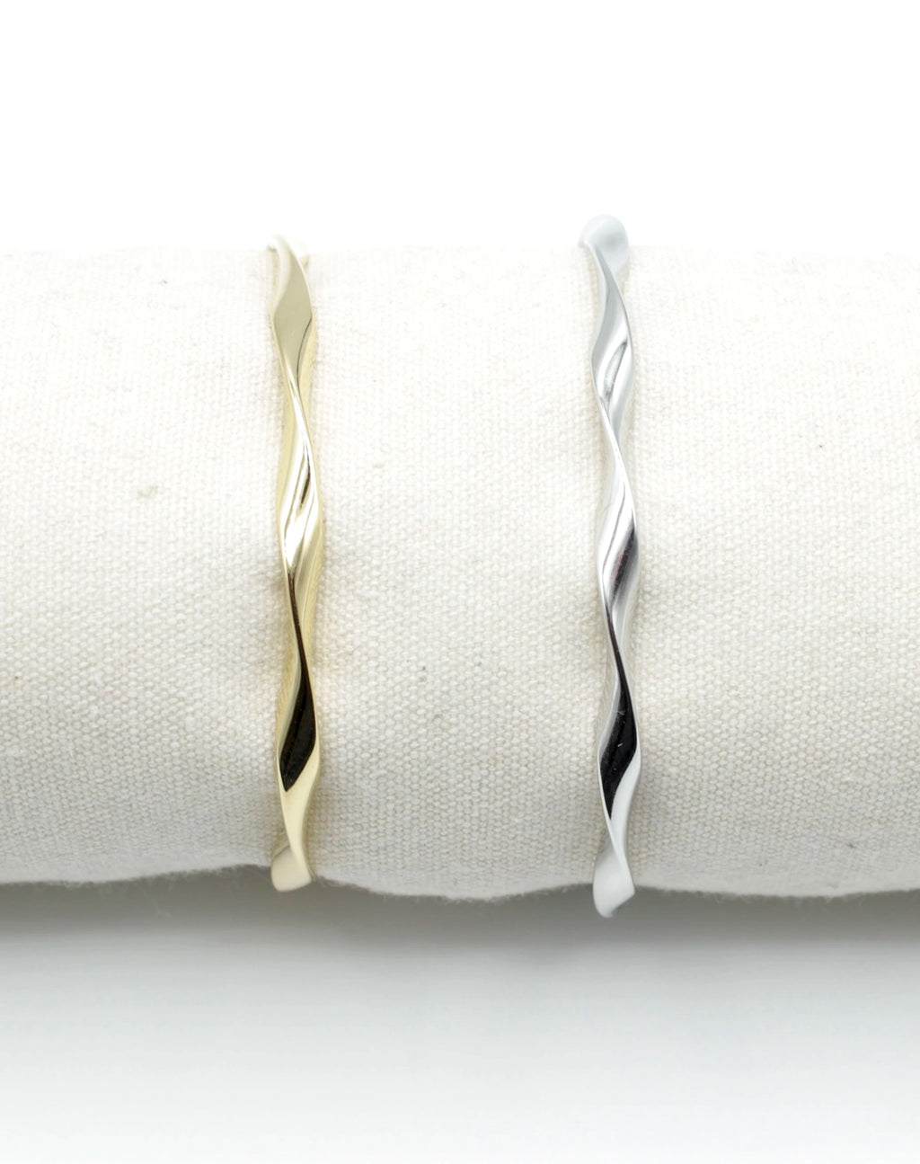 Brazaletes Acqua en acero inoxidable dorado y plateado colocados sobre cojín blanco, diseño retorcido elegante, hipoalergénicos, resistentes al agua, ajustables y duraderos -DELACABRA