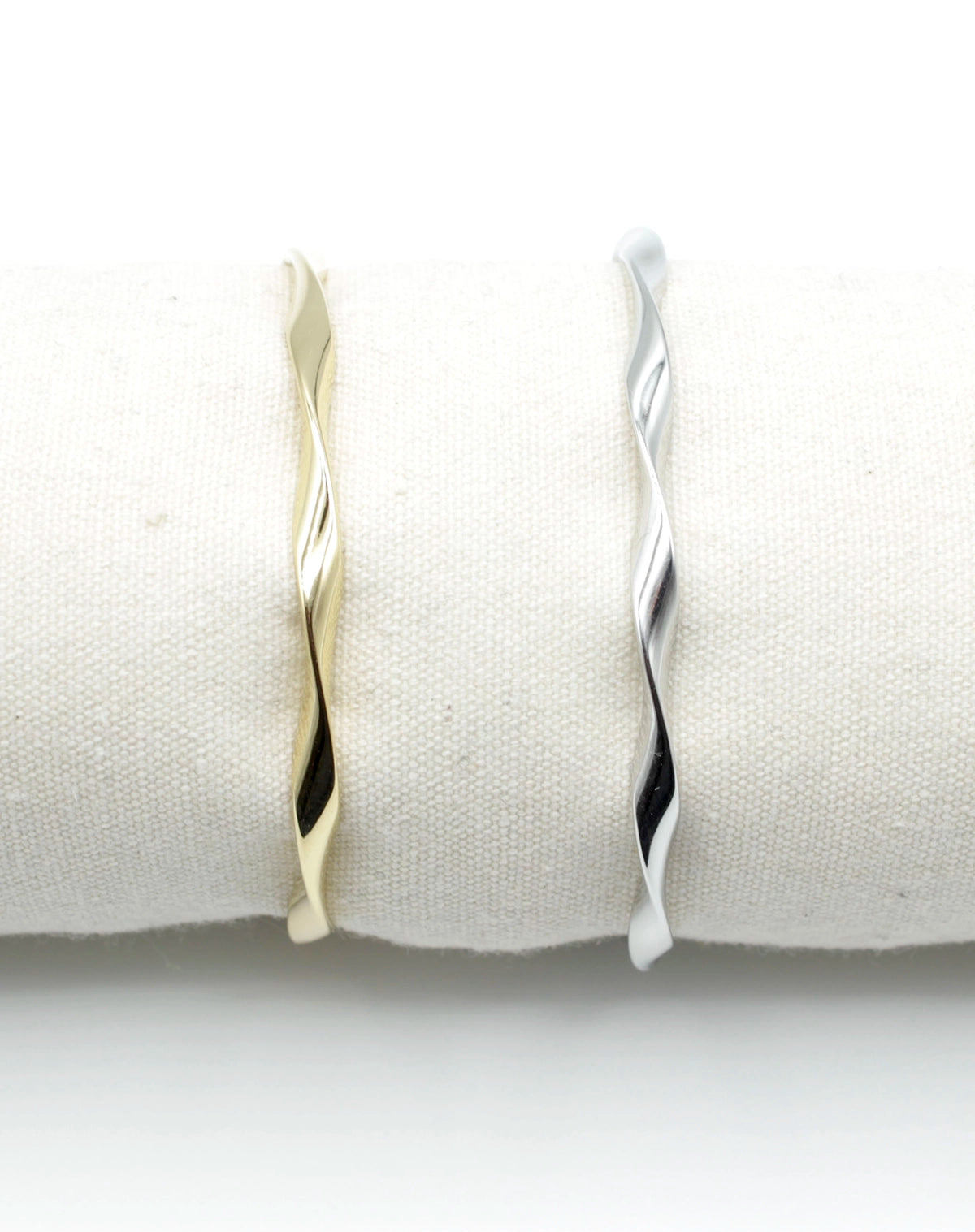Brazaletes Acqua en acero inoxidable dorado y plateado colocados sobre cojín blanco, diseño retorcido elegante, hipoalergénicos, resistentes al agua, ajustables y duraderos -DELACABRA
