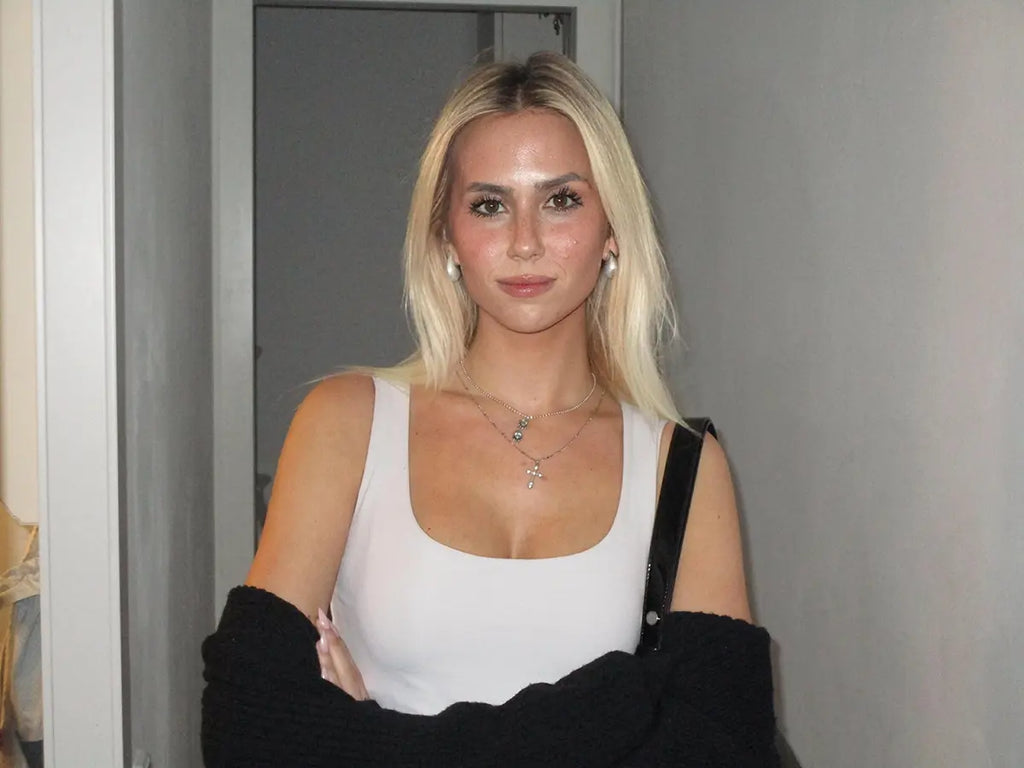 Collar Cross acero inoxidable plateado mujer joven luciendo en combinación con otro collar y pendientes. DELACABRA