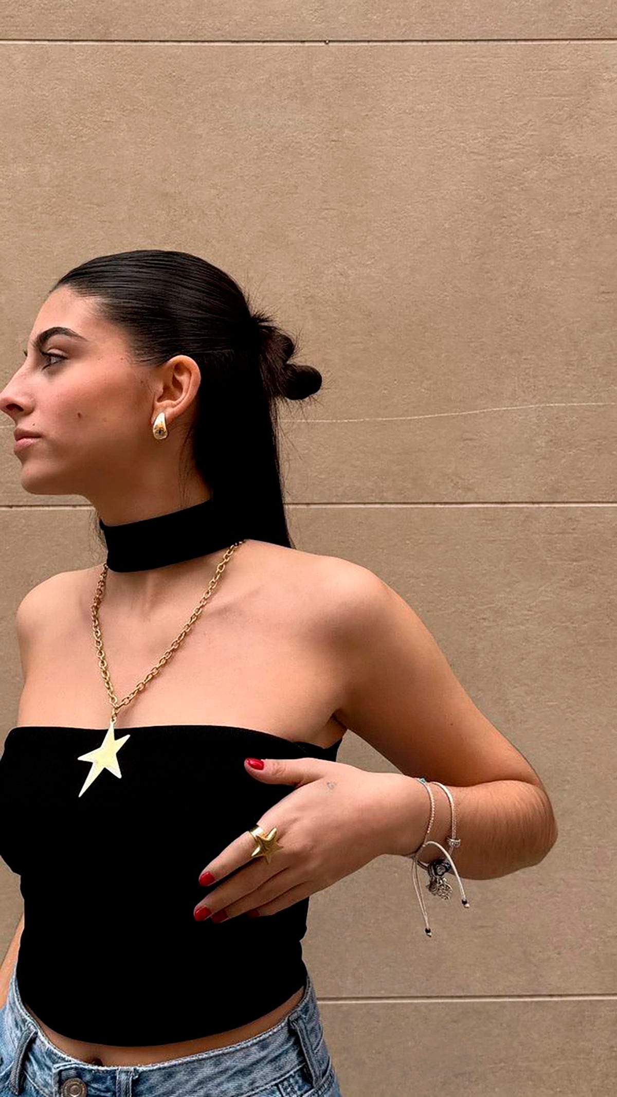 Mujer con collar de estrella grande en acero inoxidable dorado, aro dorado y anillo estrella.