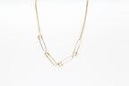 Collar de acero inoxidable dorado con eslabones tipo imperdibles sobre fondo blanco