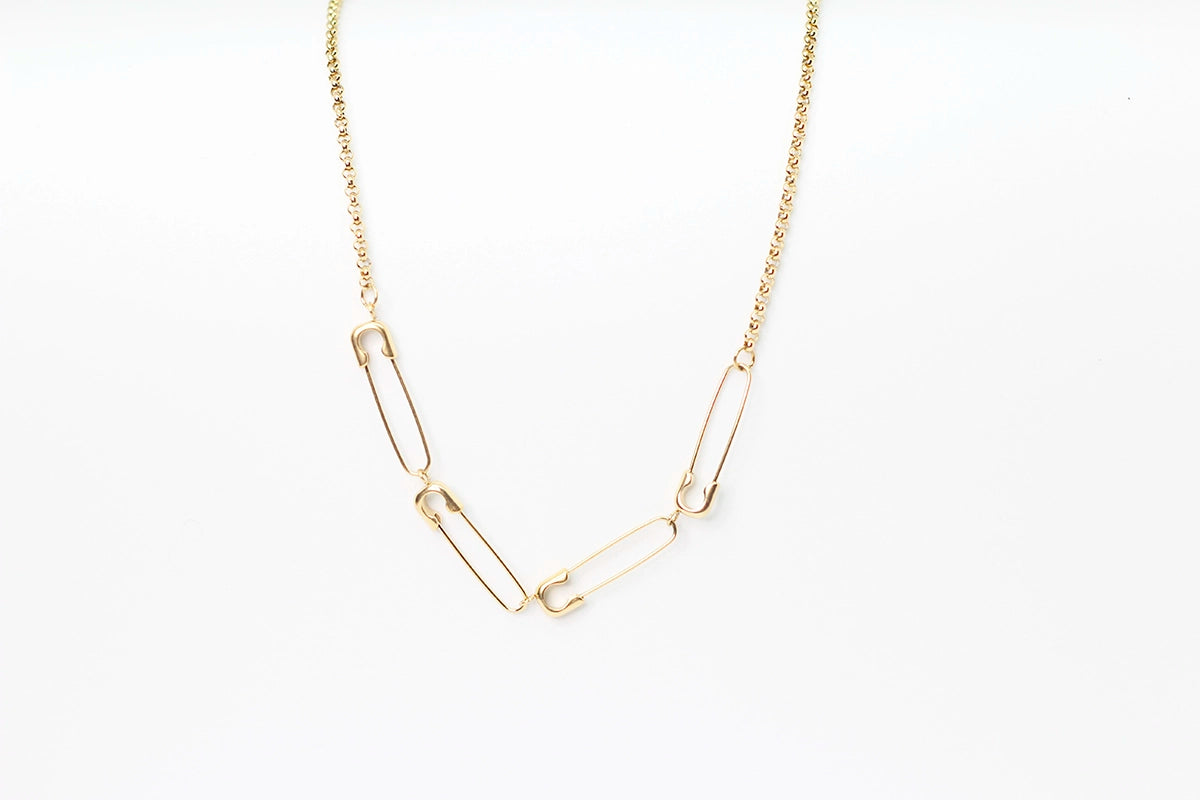 Collar de acero inoxidable dorado con eslabones tipo imperdibles sobre fondo blanco