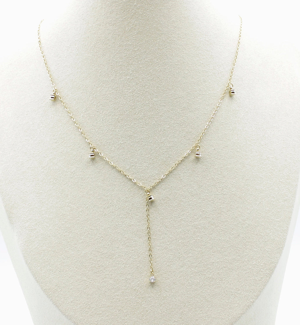 Collar Isla acero inoxidable dorado en busto, elegante y sutil, tiene una caída frontal que termina en una circonita blanca, perfecto para usarse en cuellos V - delacabra