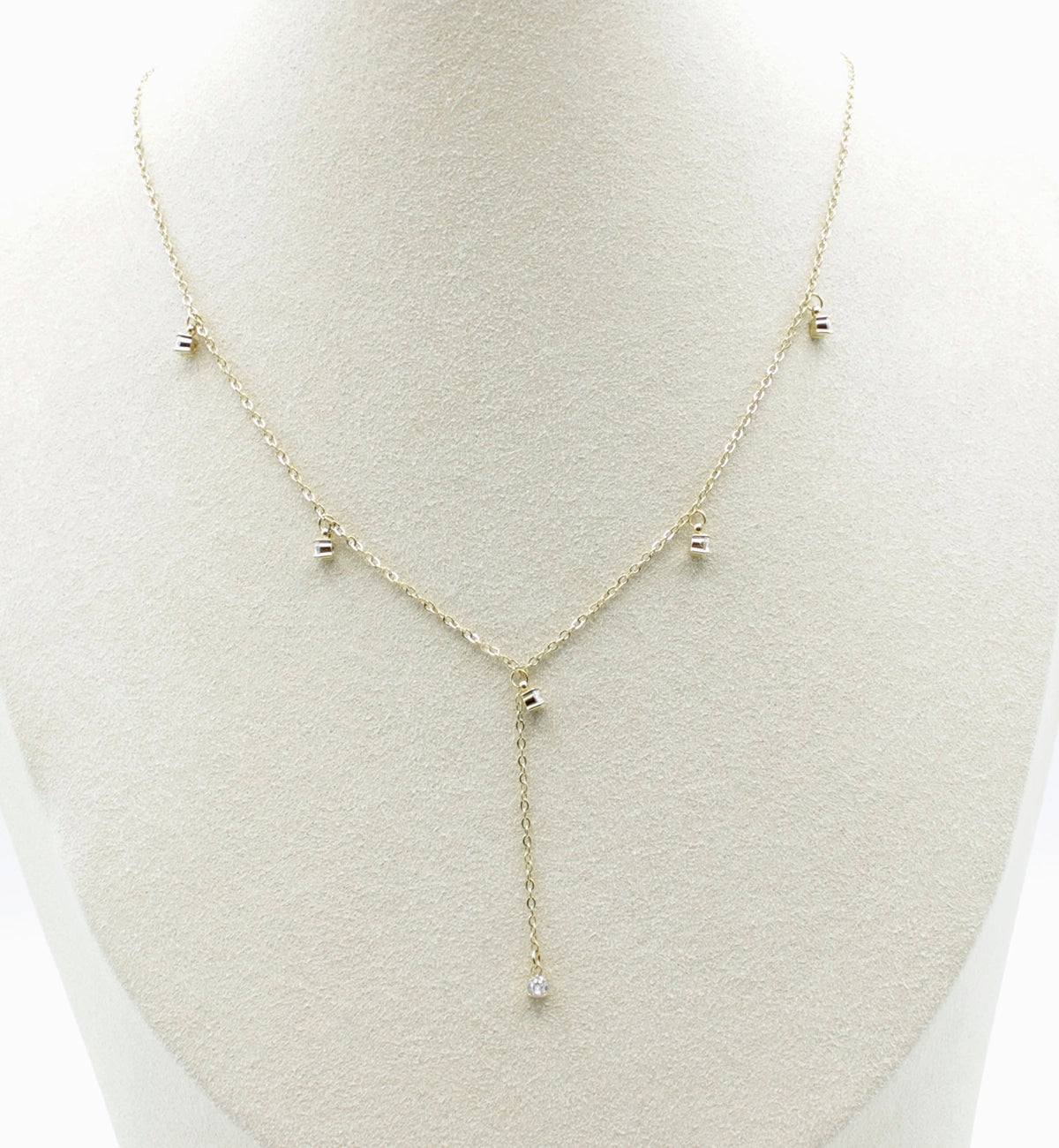 Collar Isla acero inoxidable dorado en busto, elegante y sutil, tiene una caída frontal que termina en una circonita blanca, perfecto para usarse en cuellos V - delacabra