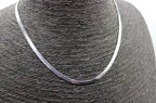 Collar de acero inoxidable plateado estilo cadena serpiente sobre busto negro.