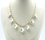 Collar Nácar acero inoxidable dorado luce en un expositor baige, clásico y atemporal, diseño que combina elegancia y audacia. - delacabra