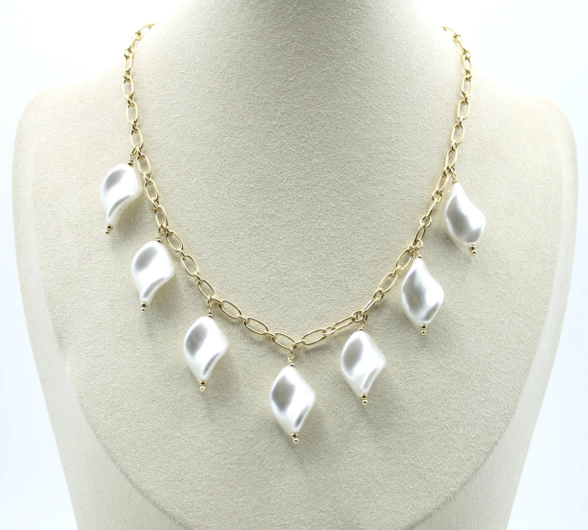 Collar Nácar acero inoxidable dorado luce en un expositor baige, clásico y atemporal, diseño que combina elegancia y audacia. - delacabra