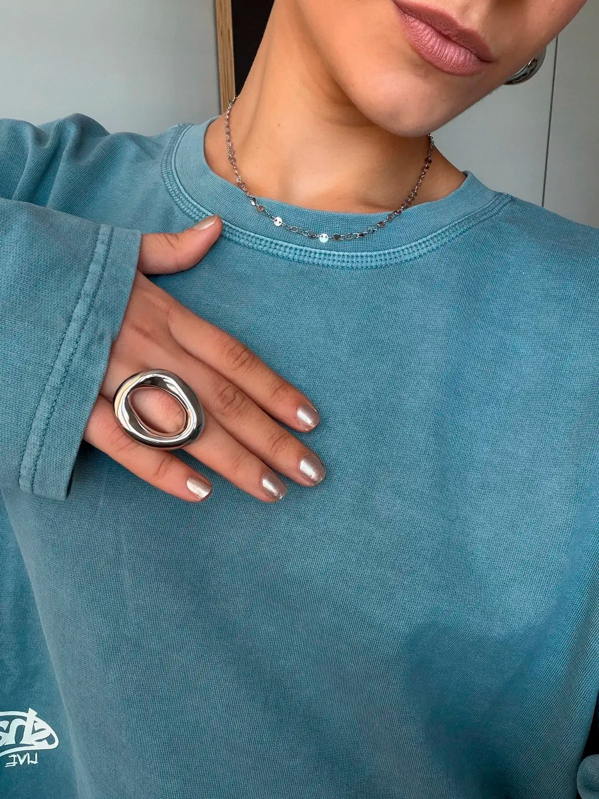 Collar zaira acero inoxidable plateado, mujer on jersey azul anillo saturno y collar zaira de delacabra. 
