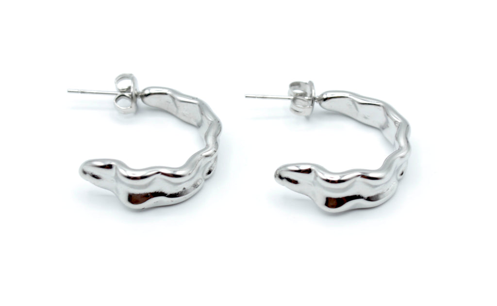 Aros Celeste plateados con forma ondulada, fabricados en acero inoxidable hipoalergénico y resistentes al agua, cierre a presión tipo mariposa.