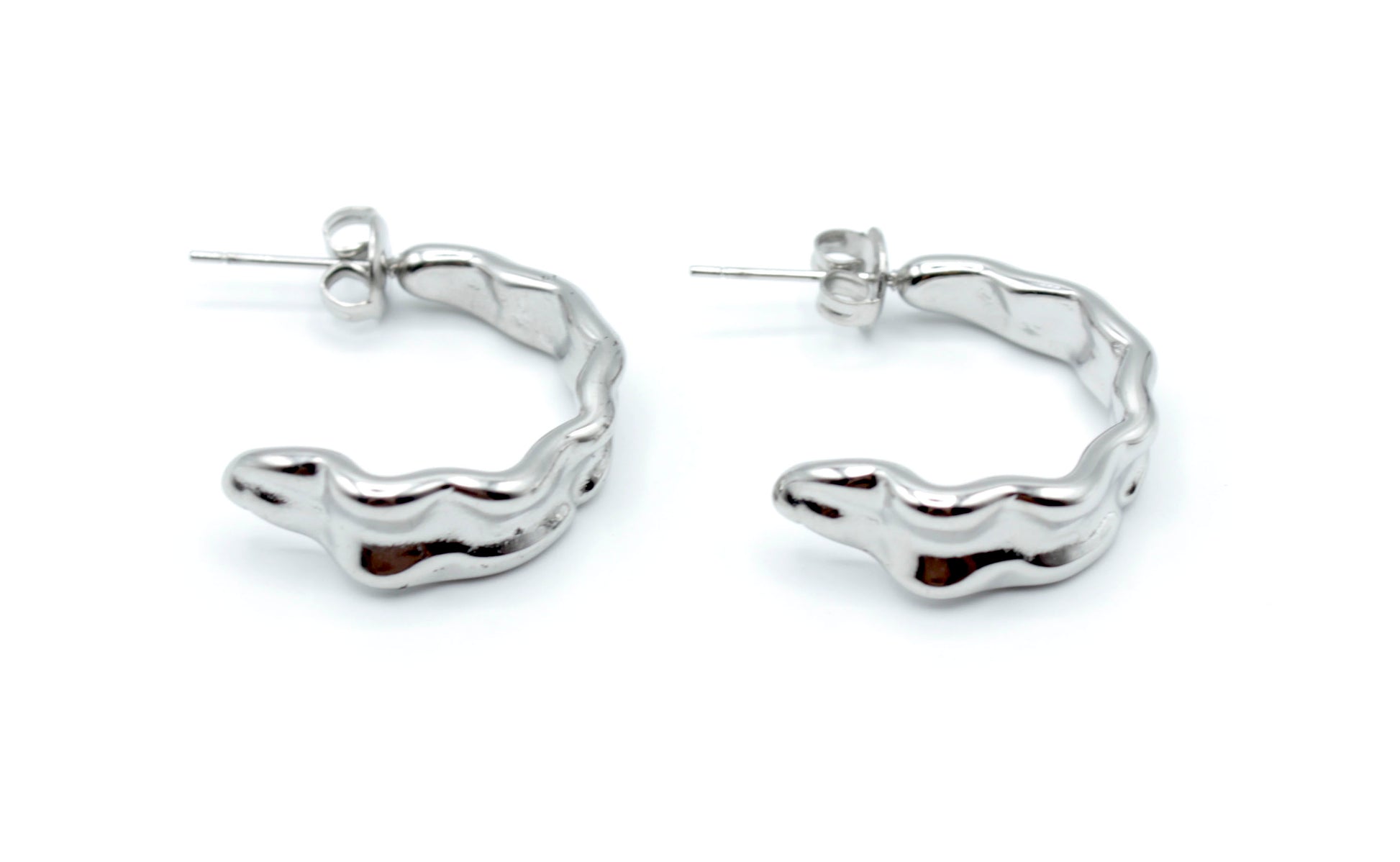 Aros Celeste plateados con forma ondulada, fabricados en acero inoxidable hipoalergénico y resistentes al agua, cierre a presión tipo mariposa.