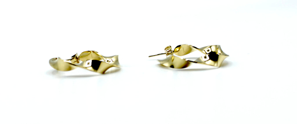 Aros River dorados con forma ondulada y diseño moderno, acero inoxidable hipoalergénico y resistente al agua, vistos en detalle.