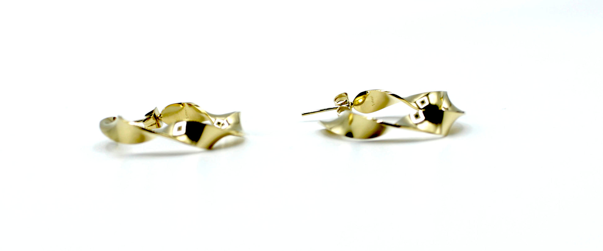 Aros River dorados con forma ondulada y diseño moderno, acero inoxidable hipoalergénico y resistente al agua, vistos en detalle.