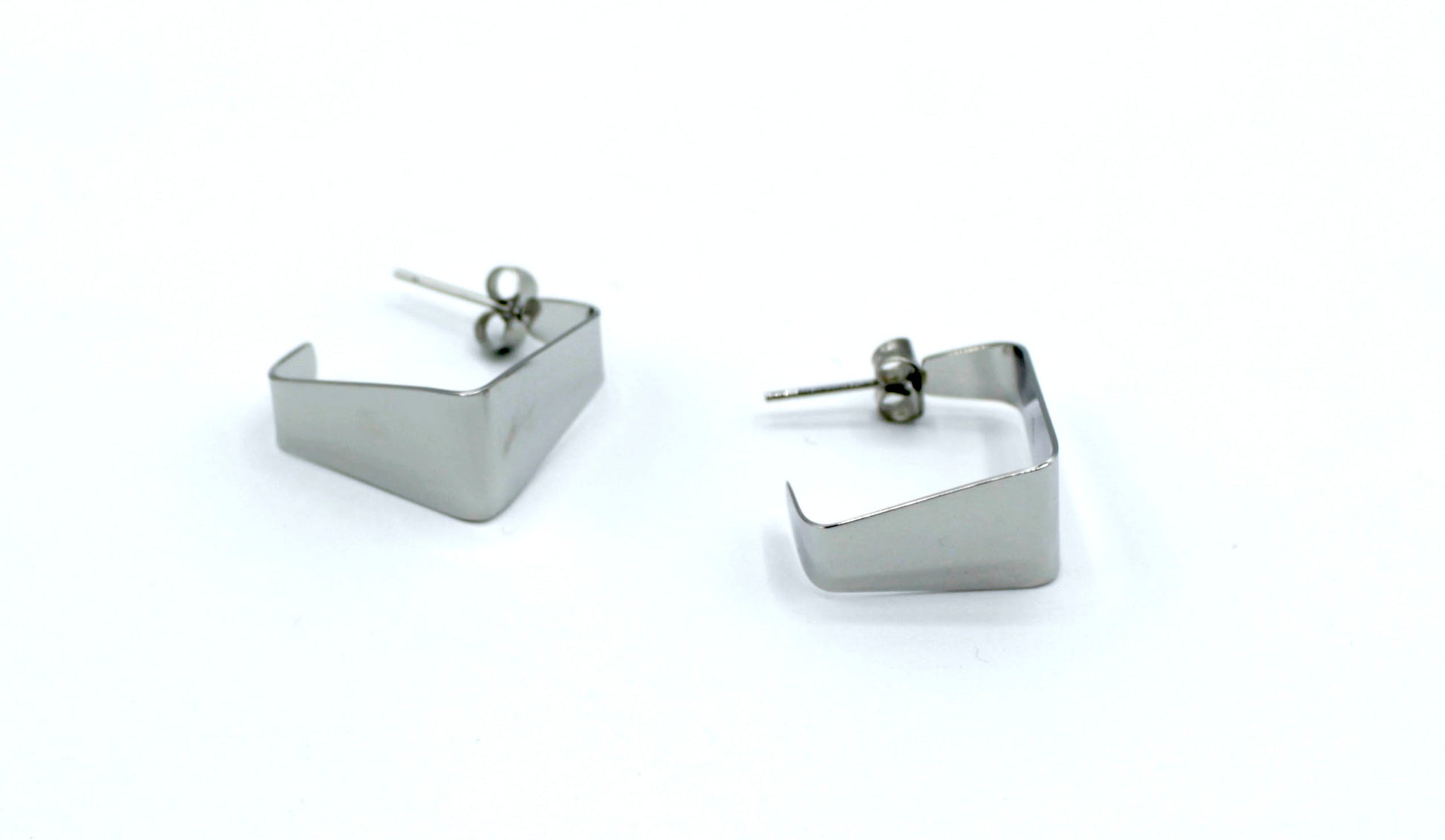 Pendientes B Square plateados de aro abierto con diseño cuadrado geométrico, fabricados en acero inoxidable hipoalergénico y resistentes al agua, cierre mariposa.